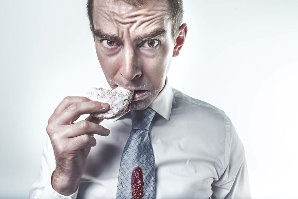 image d'un homme en chemise et cravate qui goute une galette de riz soufflé. Il a un air dégouté. Une façon d'illustrer le dégoût des régimes alimentaires et la préférence pour le rééquilibrage alimentaire.