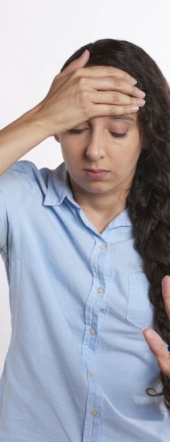 photo d'une femme qui se tient le front et qui ferme les yeux. sa main semble dire "stop" ou "non". une façon d'illustrer la frustration face à un régime. Perdre du poids grâce à l'hypnose et au coaching à Rennes